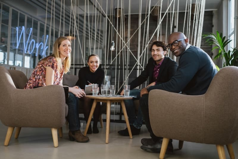 Fall and Winter Care for Commercial Rooftop Units. Image is a photograph of four coworkers sitting in an office lobby.