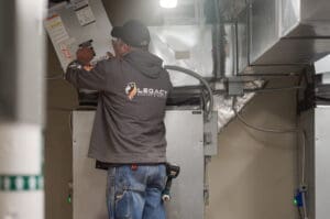 A Legacy technician inspects and replaces air filters in a commercial HVAC unit