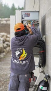 Legacy technician inspecting an outdoor commercial HVAC unit for spring prep.